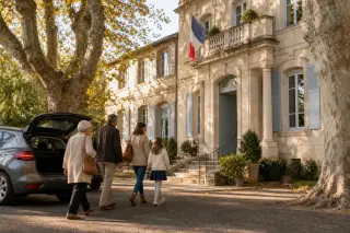 Famille et personne âgée en rendez-vous avec une conseillère administrative dans le bureau d’accueil d’une maison de retraite, avec des dossiers non lisibles sur la table.