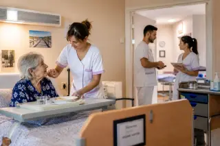 Soignant en EHPAD aidant une personne âgée dans sa chambre, illustrant le travail d’agent de soins et d’aide-soignant.
